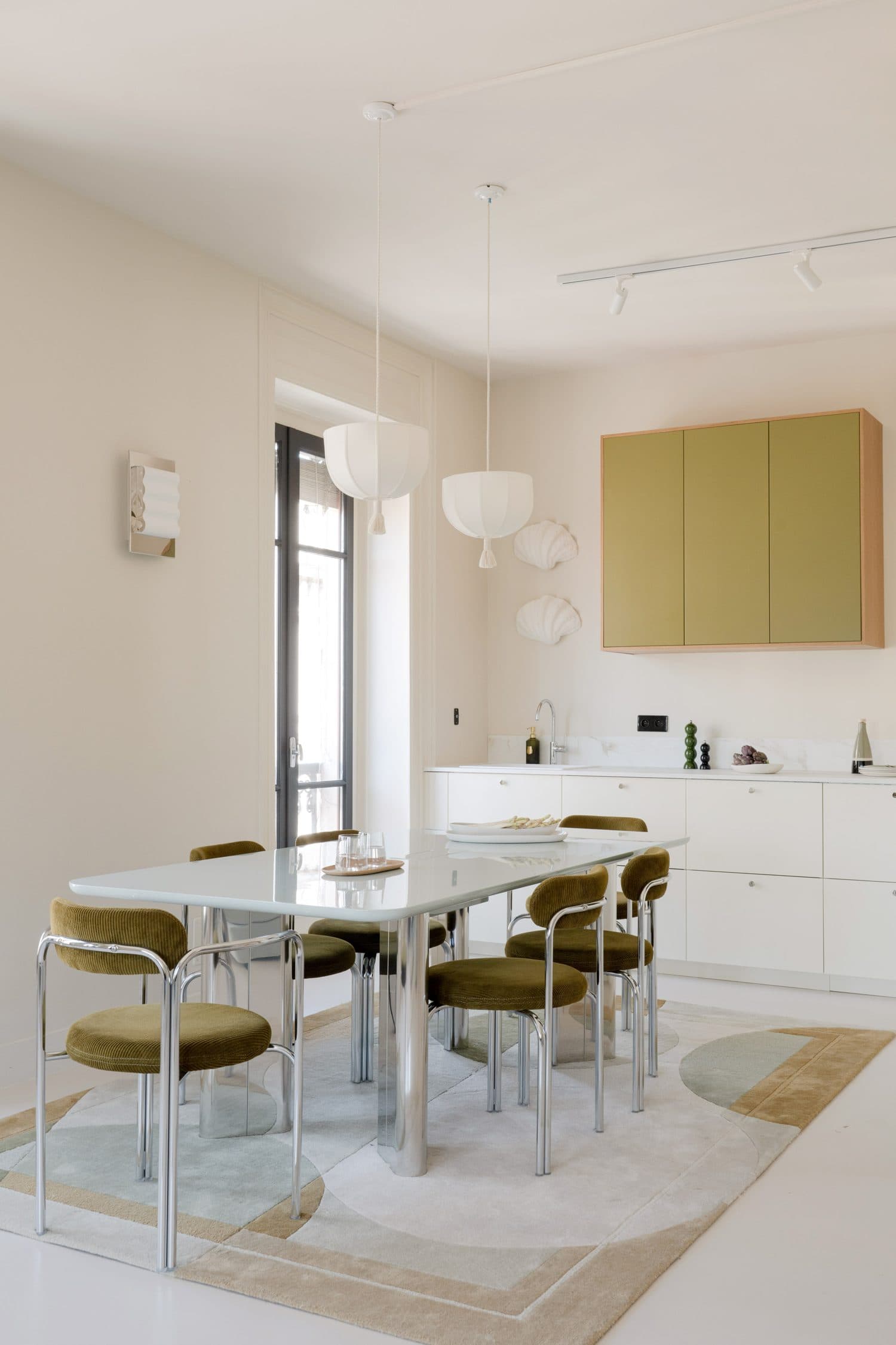 Cuisine blanche aux meubles hauts olive et coin repas chromé