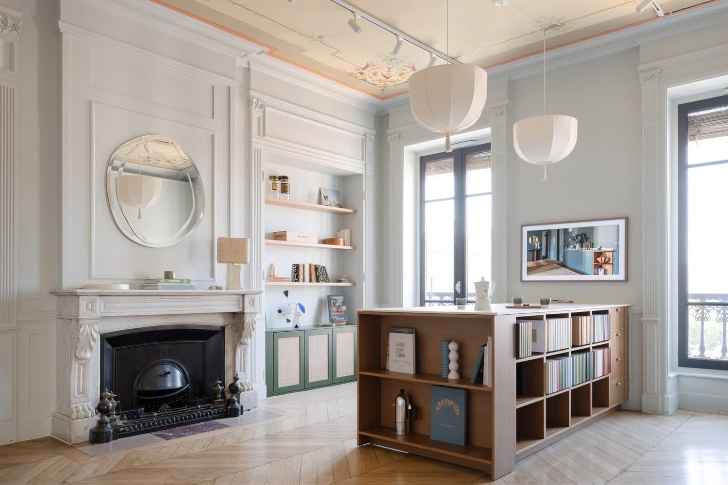 Séjour, cheminée marbre, miroir rond et îlot bibliothèque bois