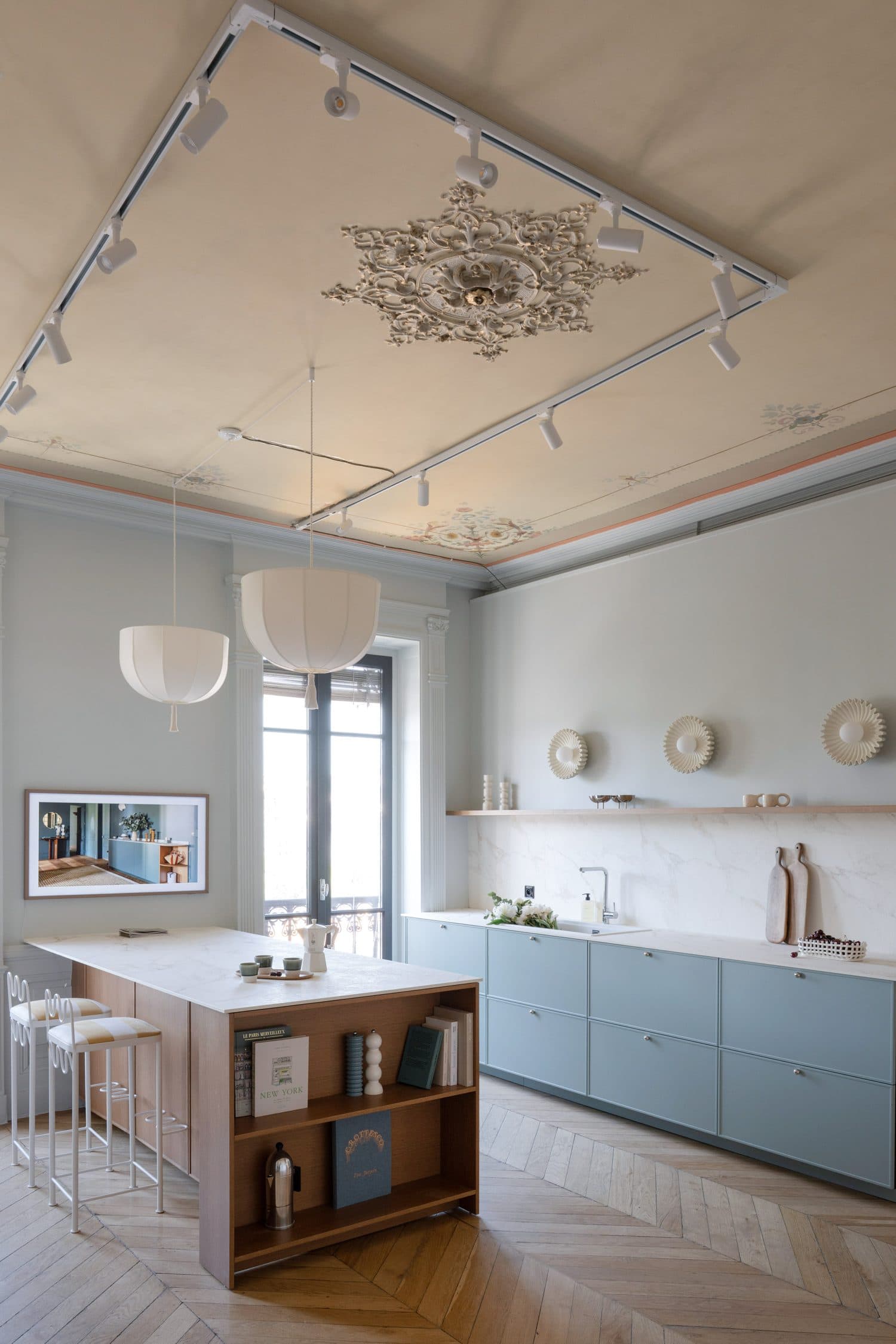 Cuisine bleu-gris, îlot bois et plan marbre sous plafond mouluré
